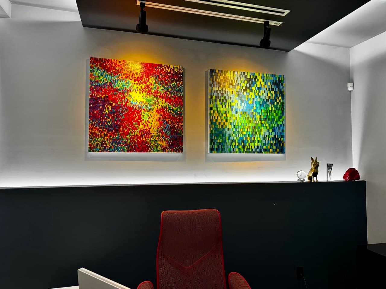 Two colorful geometric artworks illuminated by ceiling-mounted Lutron Ketra fixtures