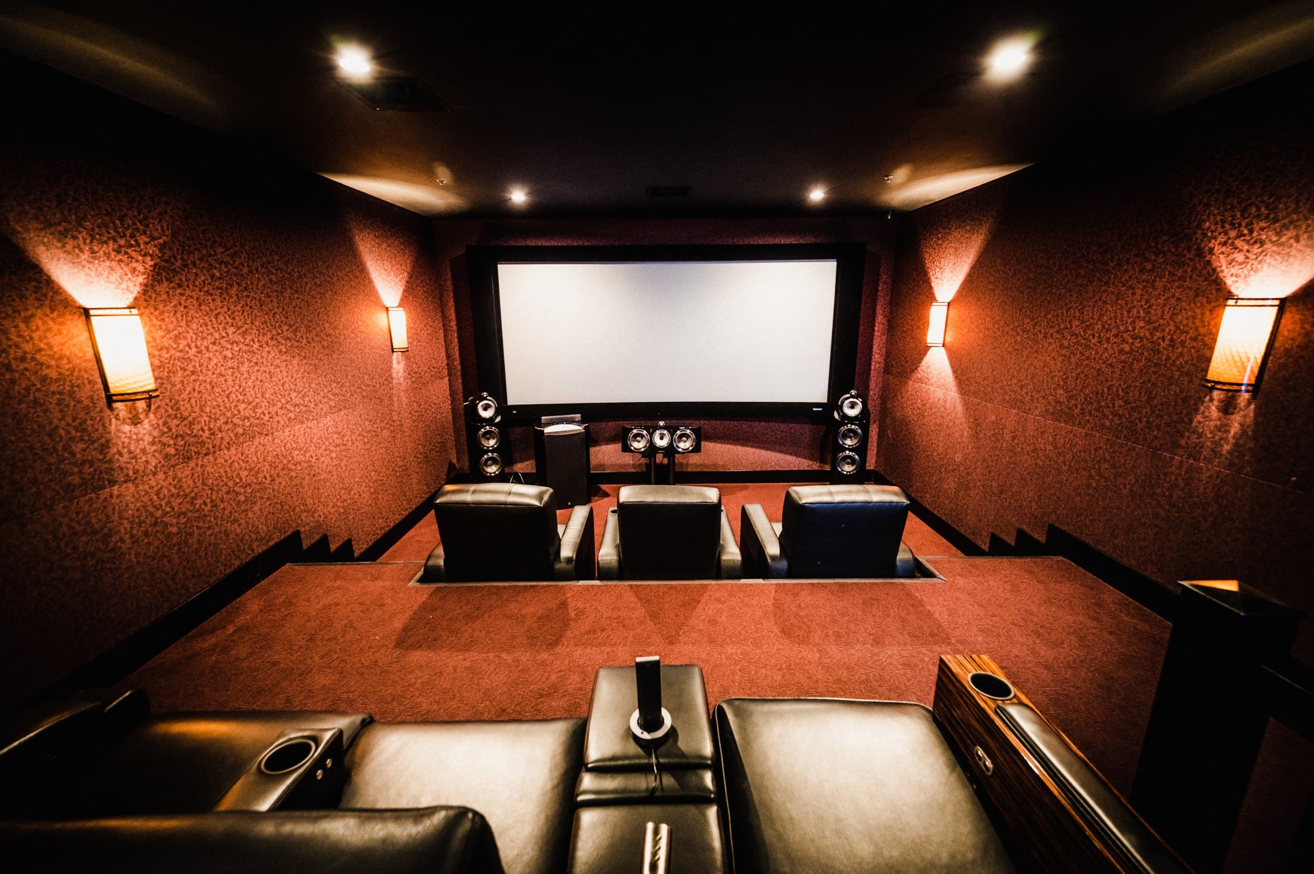 Custom home theater with Bowers & Wilkins speakers, tiered leather seating, and projection screen — Eagle Sentry Las Vegas