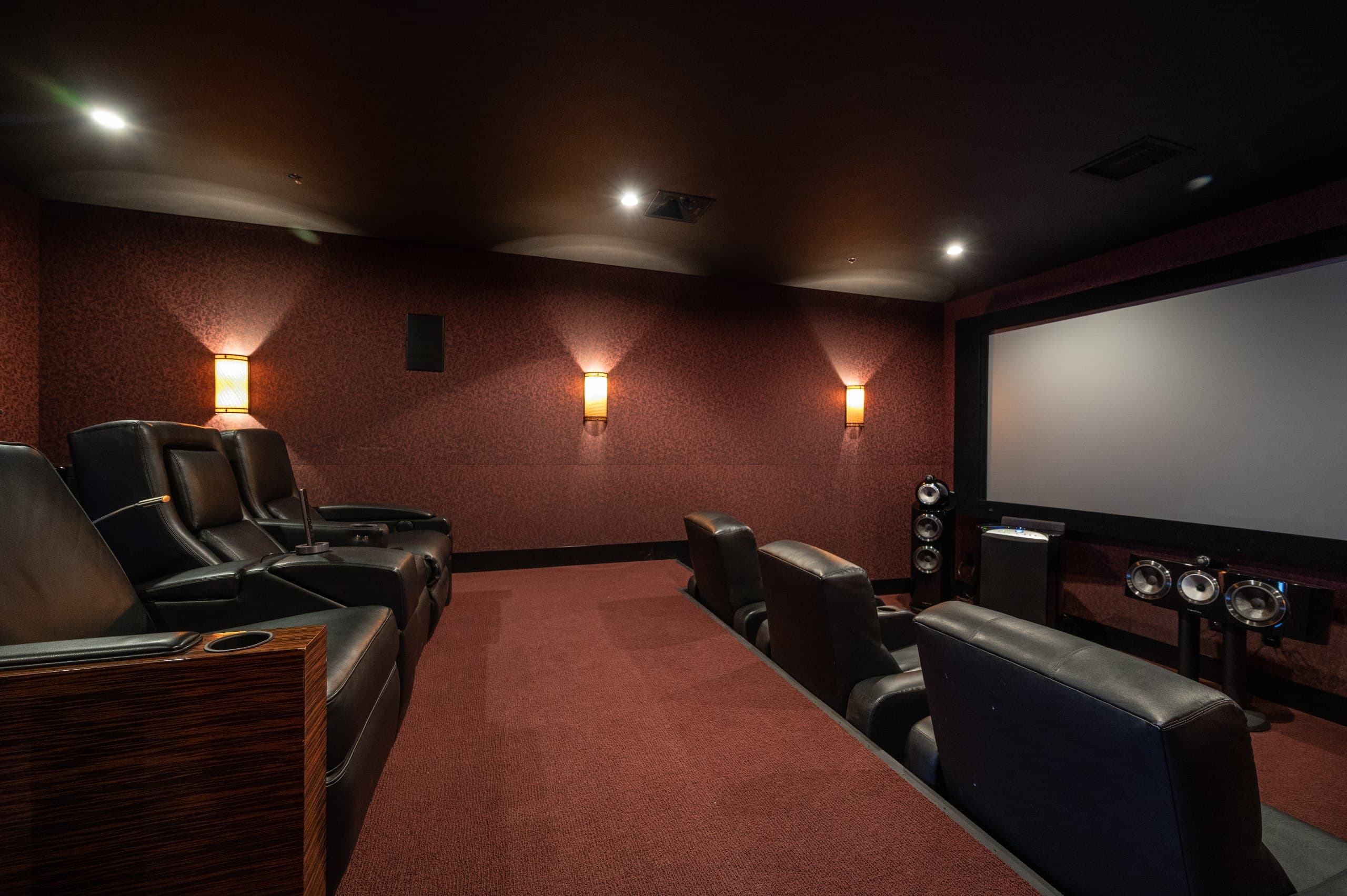 Leather theater recliners with cup holders and zebrawood armrests in a custom-built home cinema