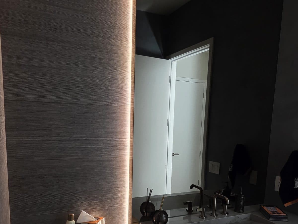 Powder bathroom with a vertical strip of LED light washing the textured wall beside the mirror