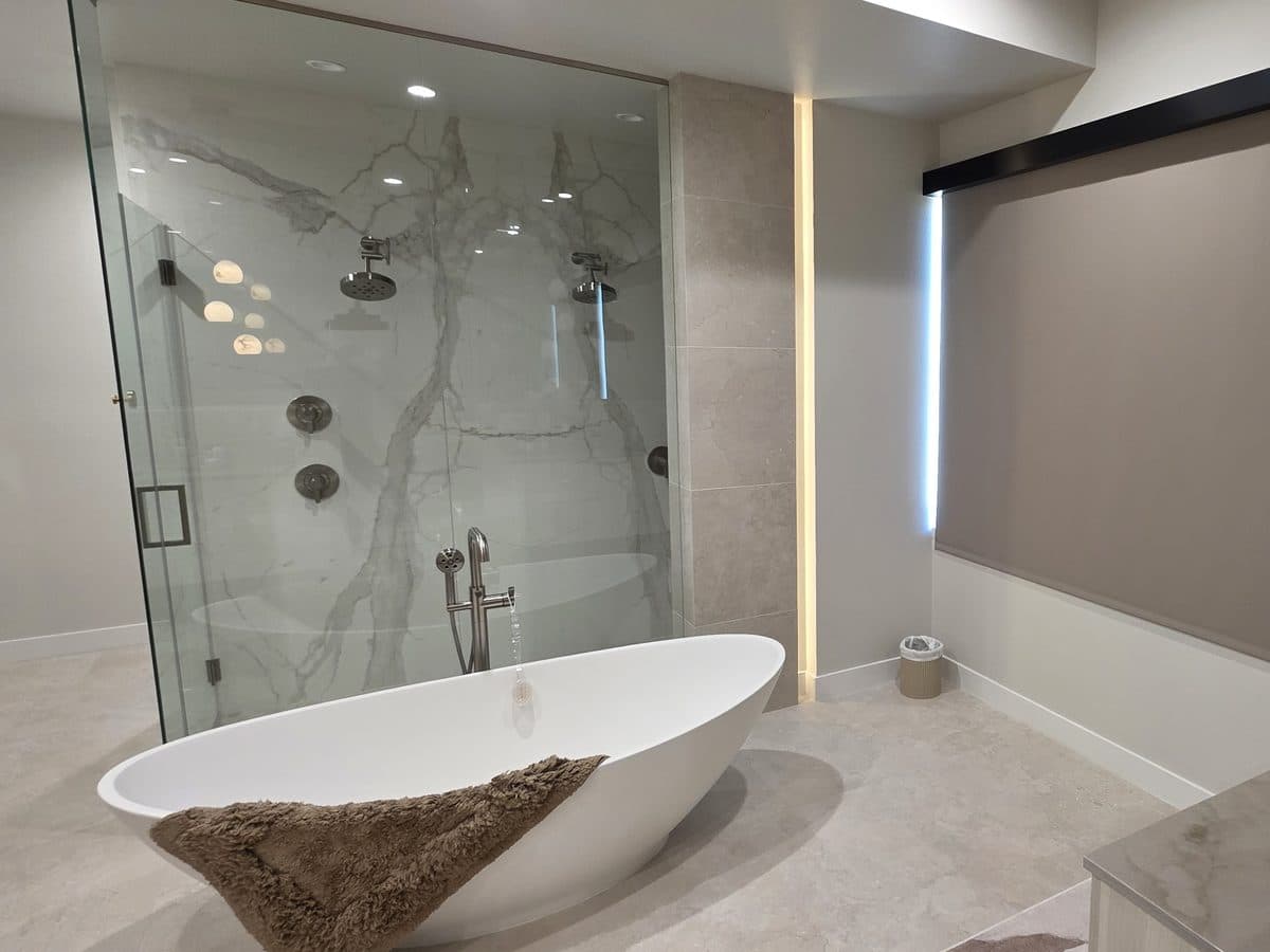 Primary bathroom with a freestanding tub under a lowered blackout roller shade