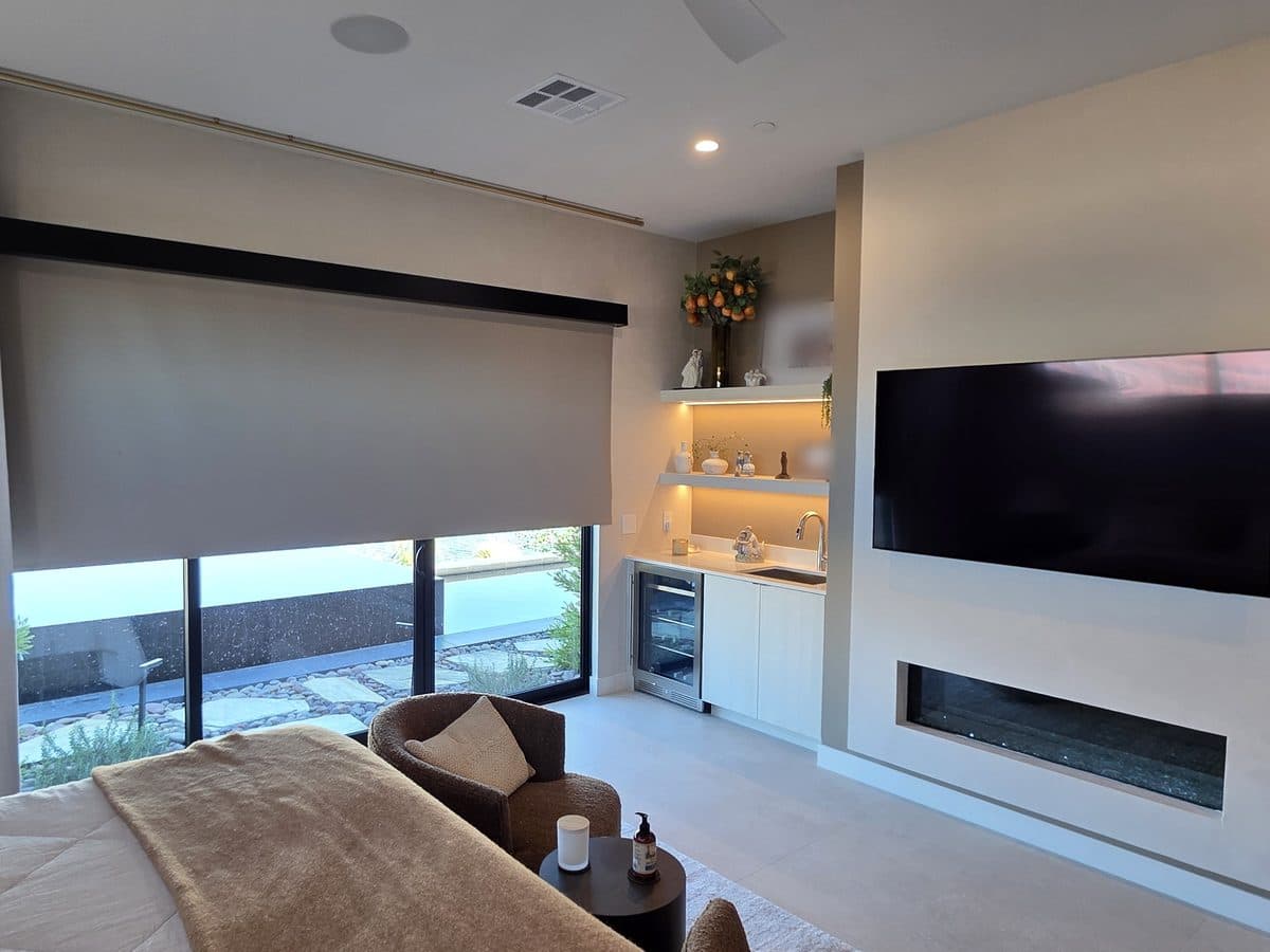 Primary bedroom with a wall-mounted Samsung TV, blackout shades and LED lighting under the coffee bar shelves