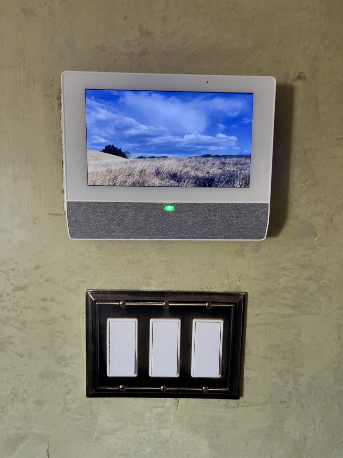 Qolsys IQ Remote 7-inch touch screen keypad mounted above a three-switch wall plate